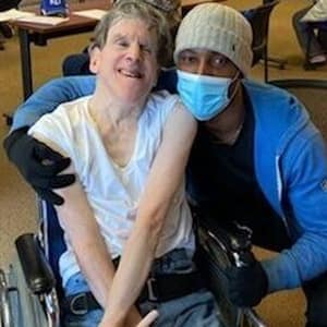 TNC Community individual smiles with staff after receiving COVID-19 vaccination